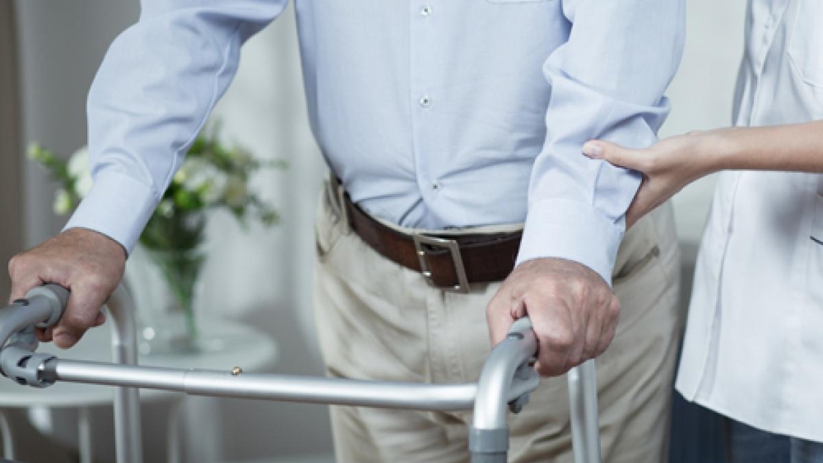 Physio assisting a patient who has a walking frame