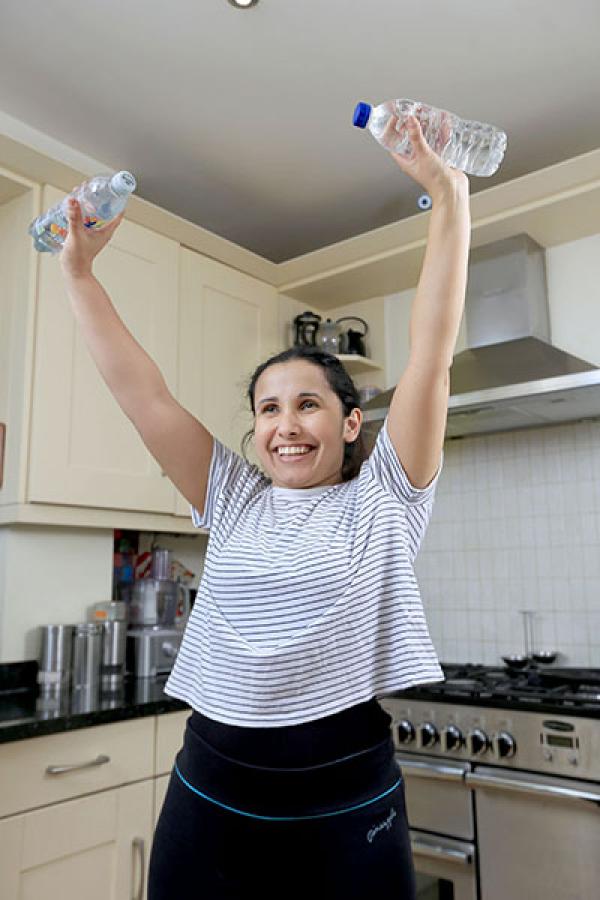 A women doing an overhead press exercise with bottles of water